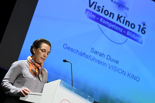 Sarah Duve, im Hintergrund Leinwand mit Kongress-Logo und Schrift "Sarah Duve"