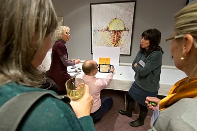 Personen arbeiten mit Laptop und einem Bild