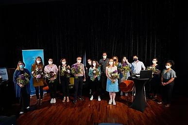 Viele Menschen mit Blumenstr&auml;u&szlig;en vor dunklem Kinovorhang