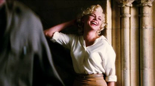 Szenenbild: Marilyn leht lachend an einem Türrahmen