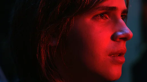 Das in rotes Licht getaucht Gesicht der Hauptfigur im Profill