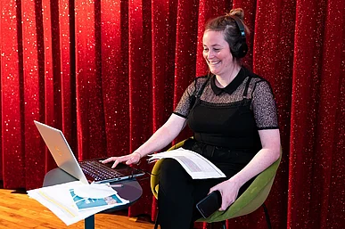 Elena Solte mit Computer vor rotem Kinovorhang