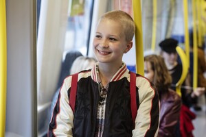 Ein Mädchen steht lachend in einer Straßenbahn. 