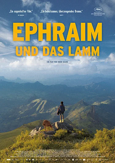 Man sieht einen Jungen, der auf einer Anhöhe steht und auf weite Täler blickt. Hinter ihm steht ein kleines Lamm. 