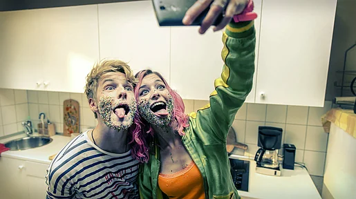 Szenenbild: Phil und seine beste Freundin Kat machen ein Selfie in der Küche, ihre Gesichter sind mit Dekostreuseln bedeckt