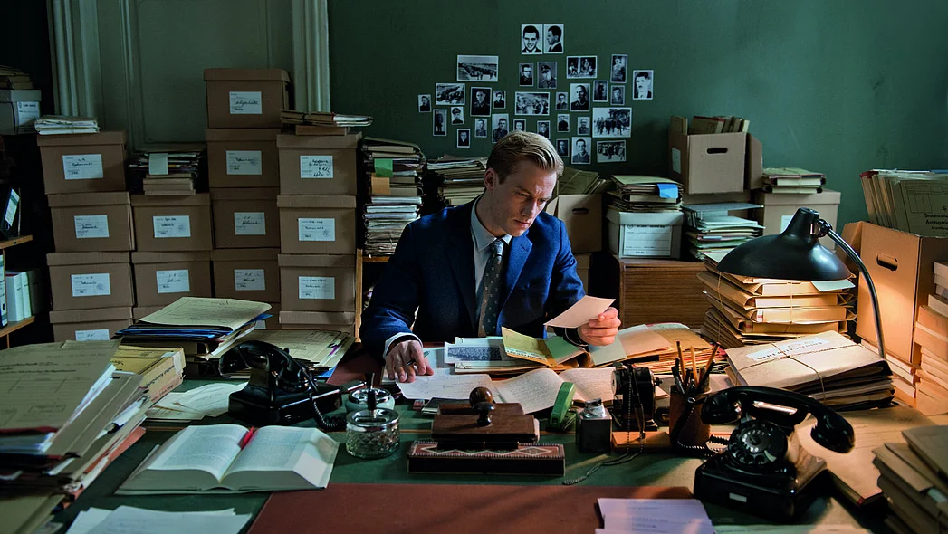 Junger Mann am Schreibtisch mit vielen Akten