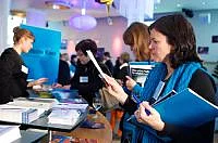 Frau informiert sich am Infostand, in der Hand eine Vision Kino Mappe