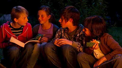 Szenenbild: Eine Kindergruppe im Schein eines Lagerfeuers