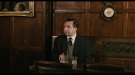 Mr. May sitzt alleine in einer Bar mit einem Whiskey.