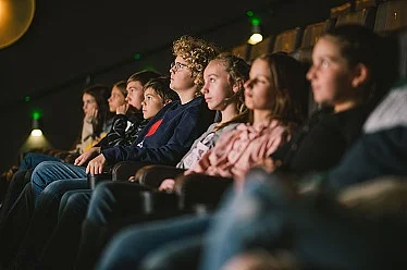 Eine Reihe von jugendlichen Zuschauer*innen in Kinosesseln sitzend