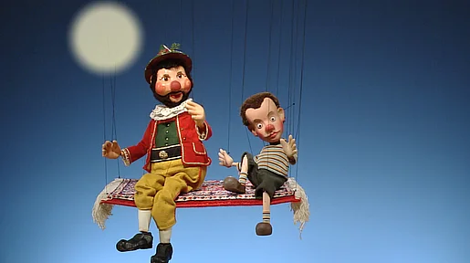 Szenenbild: Zwei Marionetten auf einer Schaukel, im Hintergrund der Vollmond