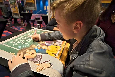 Schauspieler Luis Vorbach gibt sein Autogramm auf ein Filmplakat