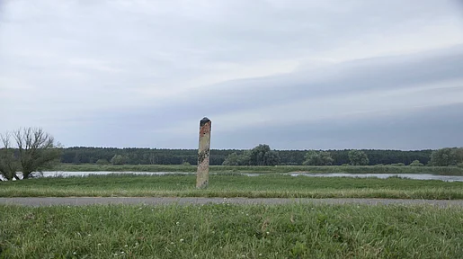 Ein Grenzpfahl in einer weiten Wiesenlandschaft