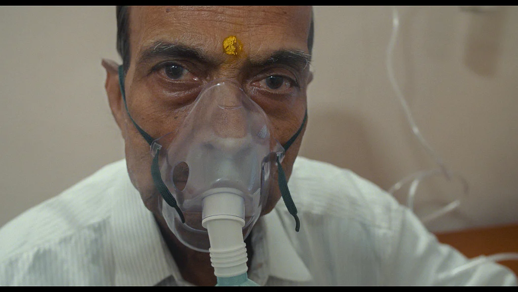 Ein Mann in Nahaufnahme blickt direkt in die Kamera, ein Beatmungsger&auml;t ist &uuml;ber seinem Mund angebracht.