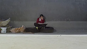 Ein M&auml;dchen sitzt lesend am Boden auf Autoreifen