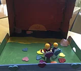 Gebasteltes Standbild von zwei Playmobilfiguren, die nebeneinander einen Sonnenuntergang anschauen, umgeben von Herzen