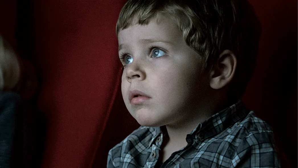 Gesicht eines kleinen Jungen in einem Kinosessel sitzt und gebannt auf die Leinwand schaut