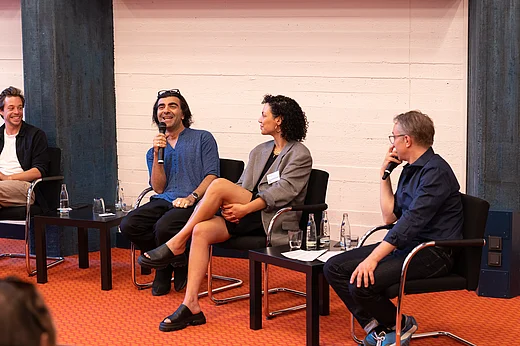 Vier Menschen auf St&uuml;hlen sitzend, Fatih Akin spricht in ein Mikrofon