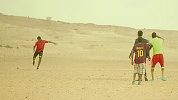 Kinder in einer w&uuml;sten&auml;hnlichen Umgebung beim Fu&szlig;ballspiel