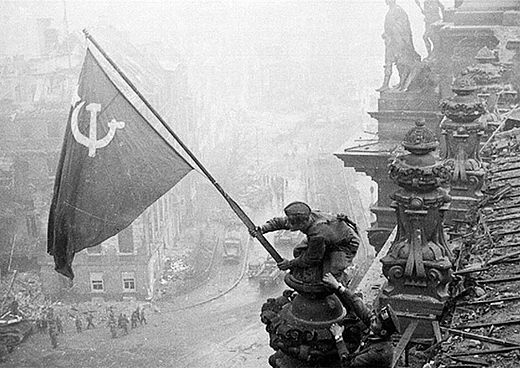 Abbildung eines Soldaten, der die rote Flagge der Sowjetunion auf dem Reichstag hisst