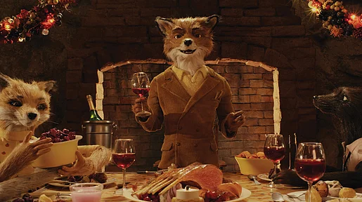 Szenenbild: Mr. Fox am Tischende mit einem Glas in der Hand