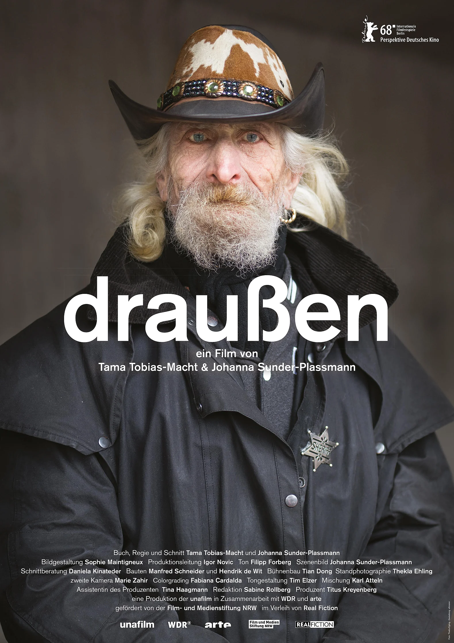 Ein alter Mann mit langen wei&szlig;en Haaren und einem Cowboyhut schaut in die Kamera.