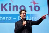 Tom Tykwer vor Leinwand mit Kongress-Dia