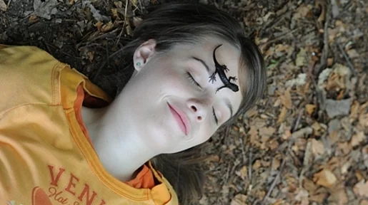 Szenenbild: Ein Mädchen liegt auf dem Boden. AUf ihrem Gesicht sitzt eine Eidechse