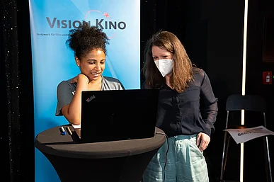 Zwei Frauen vor VISION KINO Aufsteller