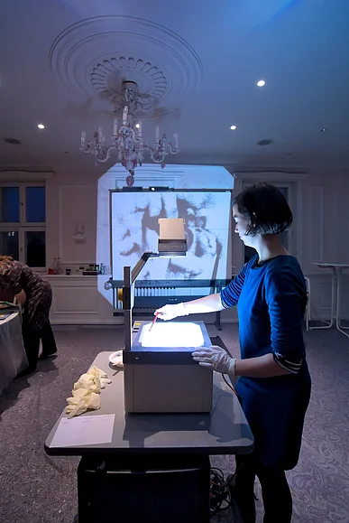 Eine Frau gestaltet eine Projektion mit Sand &uuml;ber einen Overheadprojektor