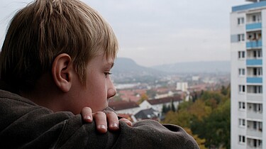 Sascha guckt traurig vom Balkon.