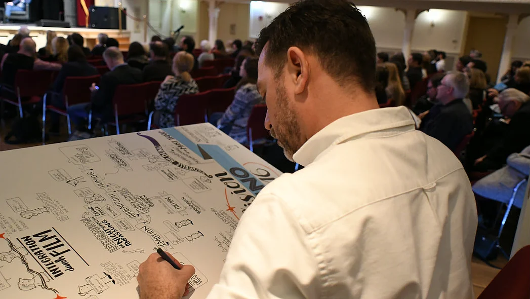 Graphic Recorder Christoph J. Kellner bei der Arbeit im Kaisersaal, von schr&auml;g hinten aufgenommen