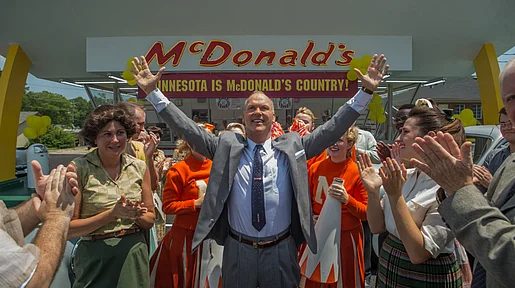 Szenenbild: Michael Keaton als Ray Kroc jubelnd inmitten einer applaudierenden Menschenmenge vor einem McDonald´s Restaurant