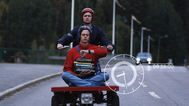 Die beiden Brüder Simon und Sam fahren mit einem motorisiertem Rad die Straße hinab. 