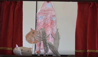 Drei gezeichnete Tierfiguren aus Papier vor einer roten Papier-Rakete, umrahmt von einem roten Vorhang