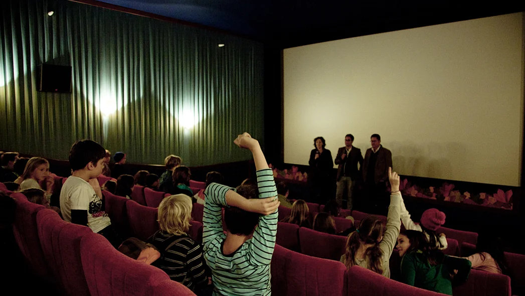 Blick zur Leinwand in einem Kinosaal, im Vordergrund meldet sich ein Kind, das von hinten zu sehen ist.