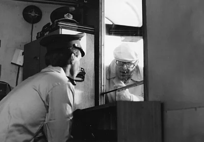 Marcel Oph&uuml;ls guckt durch ein Fenster in ein Grenzh&auml;uschen, um ein Interview mit einem Grenzer zu f&uuml;hren.