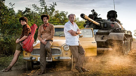Mihai, sein Vater und sein Bruder sitzen auf der Motorhaube ihres Autos, dicht dahinter ist ein Panzer zu sehen