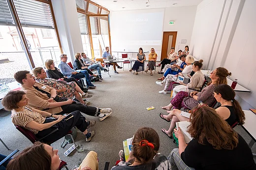 Sehr viele Personen in einem gro&szlig;en Stuhlkreis in einem gro&szlig;en Raum