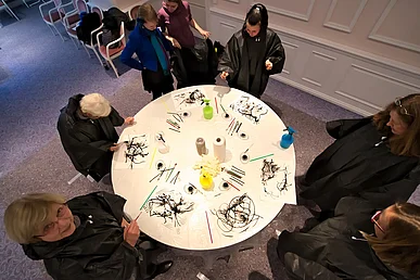 An einem Tisch wird mit Tusche gearbeitet