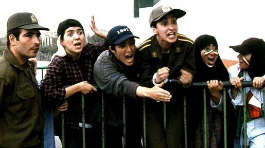 Szenenbild: als Jungs verkleidete weibliche Fußballfans feuern an einer Absperrung ihre Mannschaft an