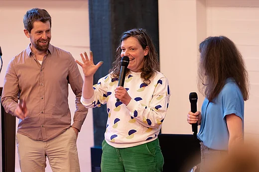 Workshopanbieterin Remke Oosterhuis spricht in ein Mikrofin, links neben ihr Michael Jahn, rechts von schr&auml;g hinten zu sehen Lisa Hau&szlig;mann