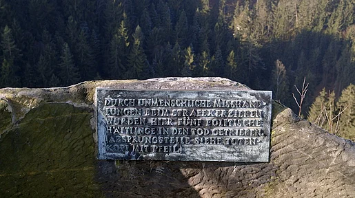 Eine Gedenktafel für getötete politische Gefangene, die in einen Fels eingelassen ist.