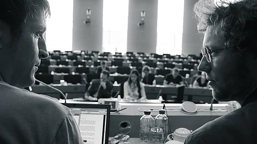 Szenenbild: Jan Philipp Albrecht und ein Kollege schauen vom Bildrand auf den Plenarsaal