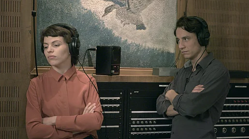 Szenenbild: die beiden Darsteller mit Kopfhörern im Tonstudio