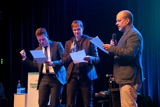 Auf der B&uuml;hne lesen Moderator Tim Gailus, Drehbuchautorin Natja Brunckhorst und Produzent Philipp Budweg vom Blatt