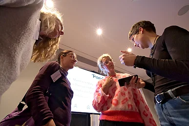 Aus der Untersicht sieht man vier Personen, die mit einem Handy arbeiten