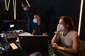 Drei Menschen mit Masken am Videomischpult