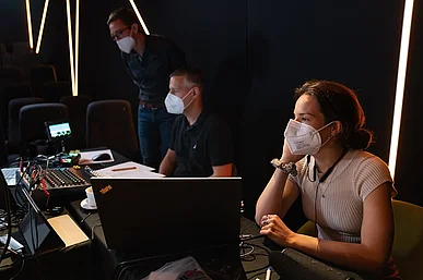 Drei Menschen mit Masken am Videomischpult