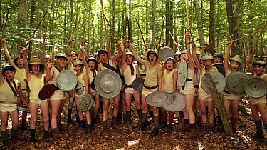 Die Kinder, bewaffnet mit Schild und Schwert und in ihrer Unterwäsche, jubeln.